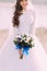 Beautiful fabulous curly bride with stylish bouquet standing on the beach.