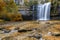 Beautiful fall forest landscape with idyllic waterfall and pool