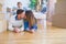 Beautiful famiily with kid lying down at new home around cardboard boxes