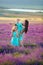 Beautiful family of cute girls enjoy life with girl power on sunset meadow of lavender. Walking mom and daughters in the field of