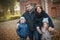 A beautiful family - dad, mom, daughter and son are standing on the street near a brick building on an autumn street, warmly