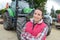 Beautiful farmer proudly posing in front tractor