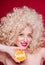 Beautiful fashionable blonde girl in retro style with voluminous curly hairstyle, bare shoulders and an orange in her hands looks