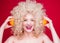 Beautiful fashionable blonde girl in retro style with voluminous curly hairstyle, open shoulders holding orange slices in hands in