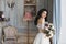 Beautiful fashionable bride, young model brunette woman in stylish wedding dress with naked shoulders with bouquet of flowers in h