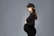Beautiful fashionable girl pregnant in studio stands posing