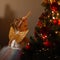 Beautiful fashionable little girl in a cute unicorn costume with golden wings on her back stands near a Christmas tree with