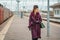 Beautiful fashionable woman on the platform waiting, gloomy autumn day