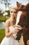 Beautiful and fashionable young bride, blonde model girl with blue eyes and stylish hairstyle in white dress posing with brown hor