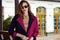 Beautiful fashionable young business woman wearing in ?rimson autumn coat and sunglasses with hairdo and makeup walking on a