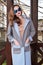 Beautiful fashionable young business woman wearing in ?rimson autumn coat and sunglasses with hairdo and makeup walking on a