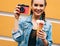 Beautiful fashionable young girl posing in a summer dress and denim jacket with pink vintage camera and multi-colored ice cream.