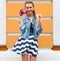 Beautiful fashionable young girl posing in a summer dress and denim jacket with pink vintage camera and multi-colored ice cream.