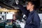 Beautiful female auto mechanic checking wheel tires in garage, car service technician woman repairing customer car at automobile