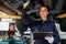 Beautiful female auto mechanic checking wheel tires in garage, car service technician woman repairing customer car at automobile