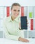 Beautiful female businesswoman showing smartphone in hand sitting at office. Selective focus.