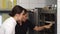 Beautiful female confectioner and her assistant examining merengues in the oven