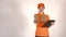 Beautiful female courier in orange uniform delivering a parcel. Light gray backround,