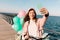 Beautiful female cyclist in pink suit makes selfie on the pier on a background of a sea landscape. Charming young