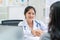 Beautiful female doctor at medical office wearing stethoscope and lab coat shaking hands with patient and smiling in hospital