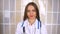 Beautiful female doctor in white coat looking at camera and smiling while standing with crossed arms