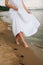 beautiful female feet on the sand a girl in a white dress walks along the shore barefoot girl