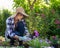 Beautiful female gardener holding a flowering plant ready to be planted in her garden. Gardening.