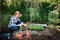 Beautiful female gardener looking at camera, holding flowers ready to be planted in her garden. Gardening.