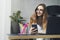 Beautiful female in glasse doing creative project on laptop. Woman sitting by computer at office desk. Digital tools and solutions