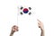 A beautiful female hand holds a South Korea flag to which she shows the finger of her other hand, isolated on white background