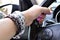 Beautiful female hand holds the steering wheel. Stylish natural bracelets on a female hand