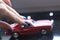 Beautiful female hand with manicure and red retro toy car . Bright blue nail polish.