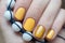 Beautiful female hand with yellow nail design.