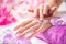 Beautiful female hands applying hand cream. Purple towel and orchid decoration. Healthy concept - Nails spa skin care