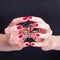 Beautiful female hands holding black metal frame diamond. Manicure with red nail polish. Black background