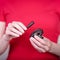 Beautiful female hands holding brown wooden ratchet money toad on a red background. Prosperity concept