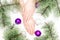 Beautiful female hands with stylish nail manicure polish on winter Christmas tree balls white background, top view