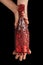 Beautiful female hands with trendy red manicure holding champagne bottle in cover spangled with vibrant red sequines on