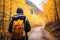 Beautiful female hiker exploring autumn forest trail with colorful fall foliage in background