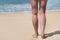 Beautiful female legs on beach, sand and sea at background