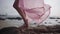 Beautiful female legs in a long developing pink dress on the seashore on the stones. close-up. 4k.