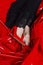 Beautiful female legs in red shoes and black dress with lace on the background of latex red fabric. Conceptual, advertising and