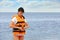 Beautiful female lifeguard putting on life vest near sea