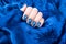 Beautiful female manicure blue. Well-groomed hands girls on blue satin tissue