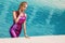 Beautiful female model dressed in long evening gowns, lies in the pool