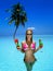 Beautiful female model in pink bikini is standing in the pool and holding colorful fruity drink. Sexy woman in sequin bikini is