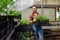 Beautiful female nursery worker working in greenhouse