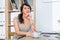 Beautiful female office worker sitting on workplace, smiling, writing down information at her organizer, drinking coffee