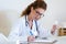 Beautiful female pharmacist holding jar of pills in hands in the office.