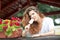 Beautiful female portrait with long brown hair eating ice cream near a pot with red flowers outdoor. Attractive woman